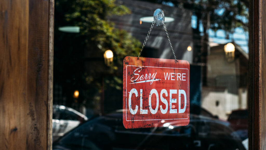 Red "sorry, we're closed:" sign hanging in a doorway